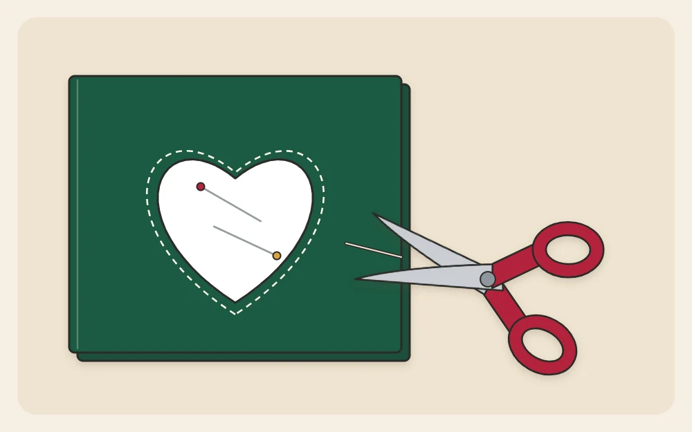 A paper template pinned to a folded piece of felt with scissors cutting around its edge