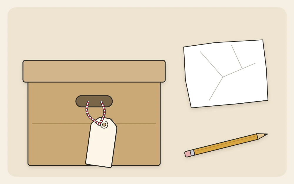 A blank label tag tied to a box handle beside a sheet of tissue paper and a pencil